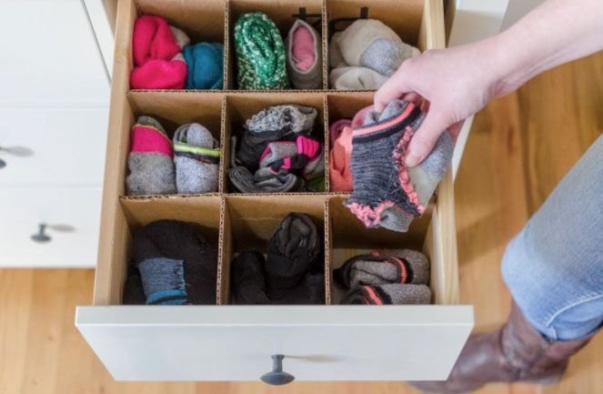 Socks are neatly placed in drawers with cardboard dividers for easy home storage